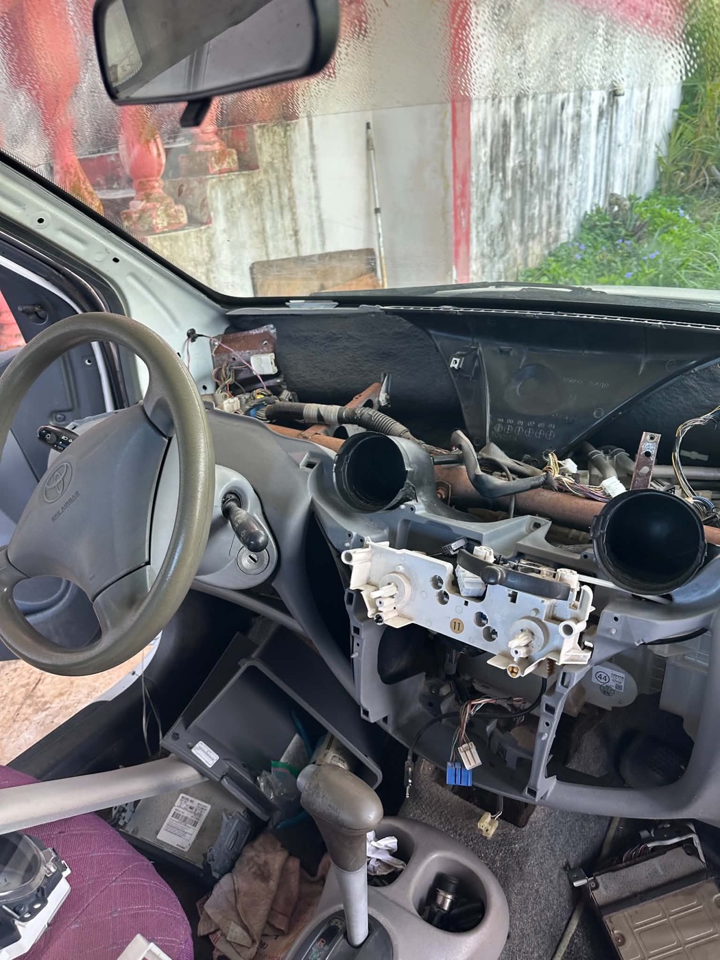 Car dashboard stripped down with the climate control panel and air ducts exposed